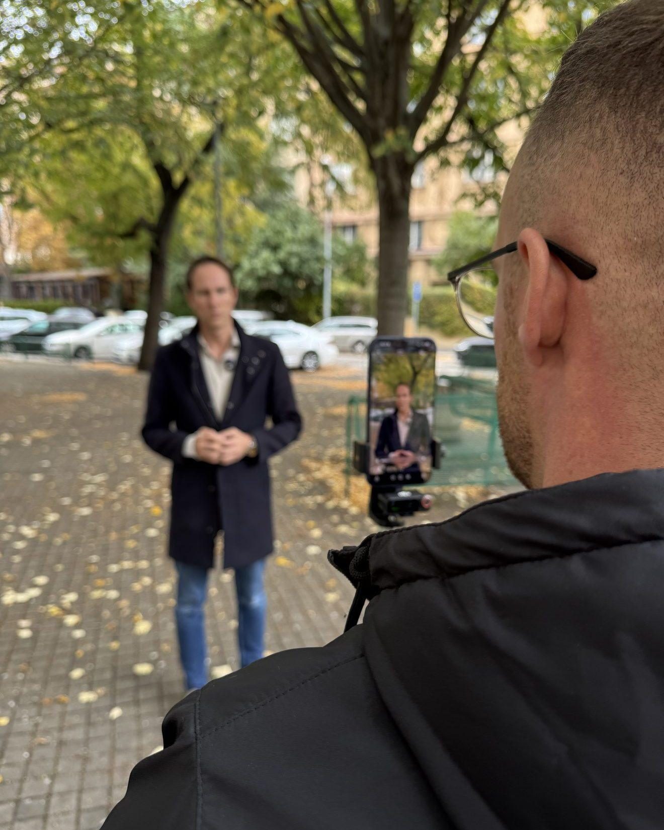 Pohled přes rameno na displej mobilu při natáčení videa